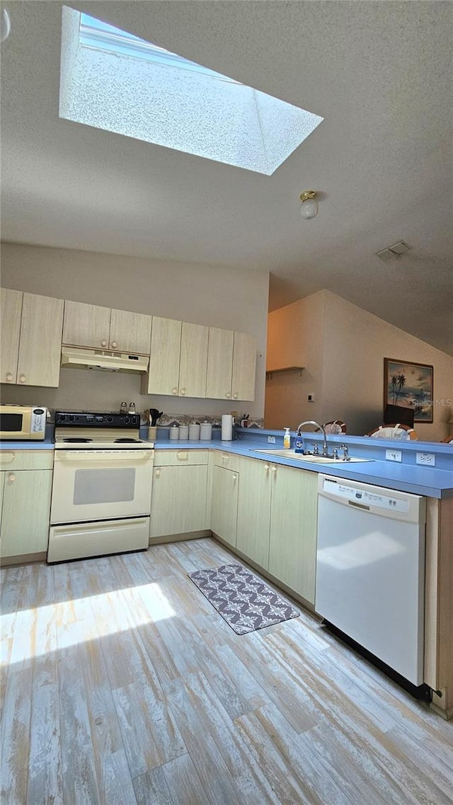 2105 Escobar Ave, The Villages, FL 32159 - kitchen with white appliances, a skylight, lofted ceiling, light wood-type flooring, and a textured ceiling