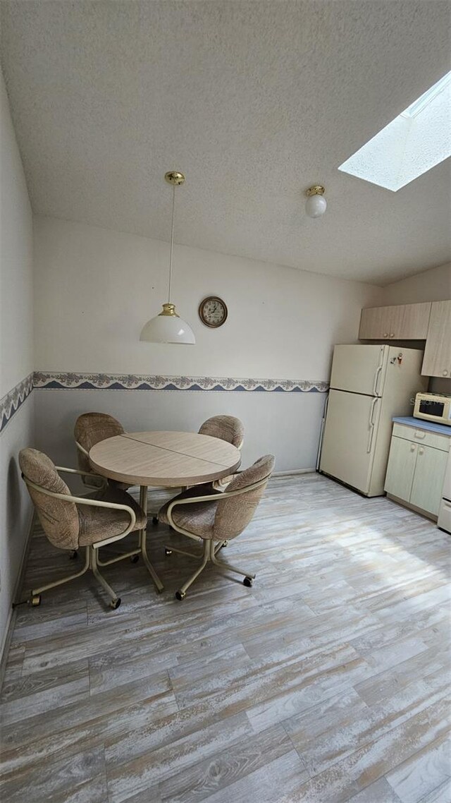 2105 Escobar Ave, The Villages, FL 32159 - dining area featuring a skylight, a textured ceiling, light wood finished floors, and breakfast area