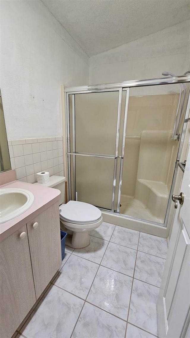 2105 Escobar Ave, The Villages, FL 32159 - full bathroom with vanity, toilet, a shower stall, tile walls, and a wainscoted wall
