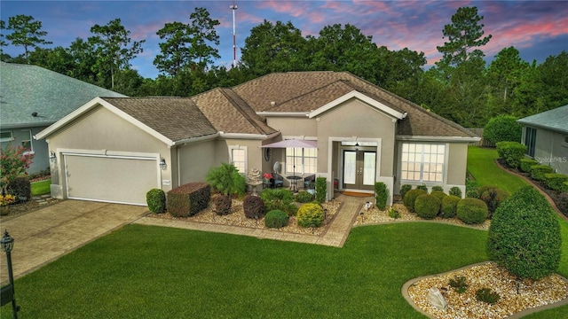 11868 SE 91st Cir, Summerfield, FL 34491 - view of front of home featuring french doors, stucco siding, a front lawn, a garage, and driveway