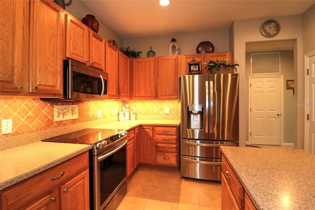 11868 SE 91st Cir, Summerfield, FL 34491 - kitchen featuring stainless steel appliances, decorative backsplash, light tile patterned floors, light stone countertops, and brown cabinets
