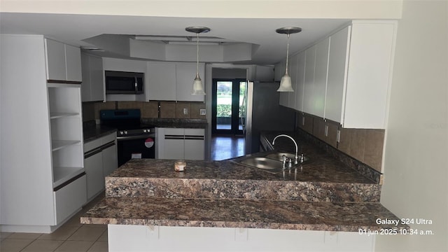 2450 Sweetwater Country Club Dr, Apopka, FL 32712 - kitchen with stainless steel appliances, a sink, a peninsula, a tray ceiling, and dark countertops