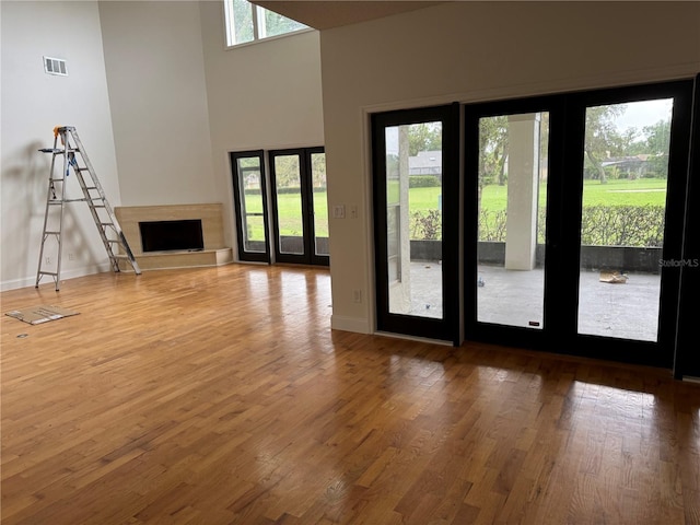 2450 Sweetwater Country Club Dr, Apopka, FL 32712 - unfurnished living room featuring wood finished floors, baseboards, a fireplace with raised hearth, and a high ceiling