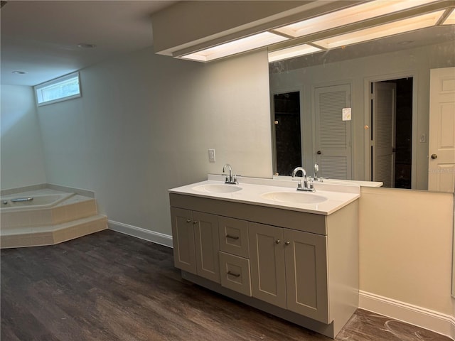 2450 Sweetwater Country Club Dr, Apopka, FL 32712 - bathroom with double vanity, a garden tub, wood finished floors, and baseboards