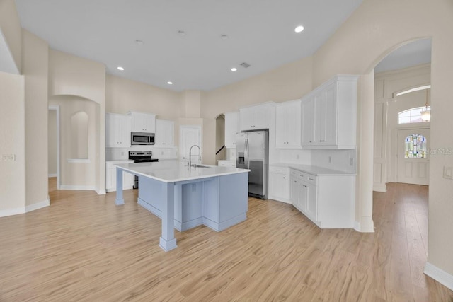 5556 Vintage View Blvd, Lakeland, FL 33812 - kitchen featuring stainless steel appliances, a sink, arched walkways, white cabinets, and a towering ceiling