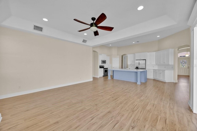 5556 Vintage View Blvd, Lakeland, FL 33812 - unfurnished living room with a tray ceiling, ceiling fan, light wood-type flooring, arched walkways, and recessed lighting