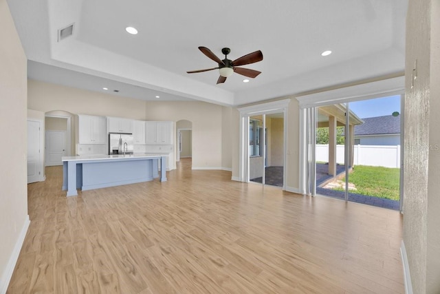 5556 Vintage View Blvd, Lakeland, FL 33812 - unfurnished living room with arched walkways, ceiling fan, light wood-style flooring, a raised ceiling, and recessed lighting