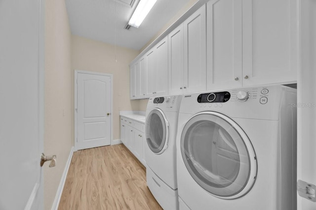 5556 Vintage View Blvd, Lakeland, FL 33812 - laundry area featuring washer and dryer, cabinet space, attic access, light wood finished floors, and baseboards