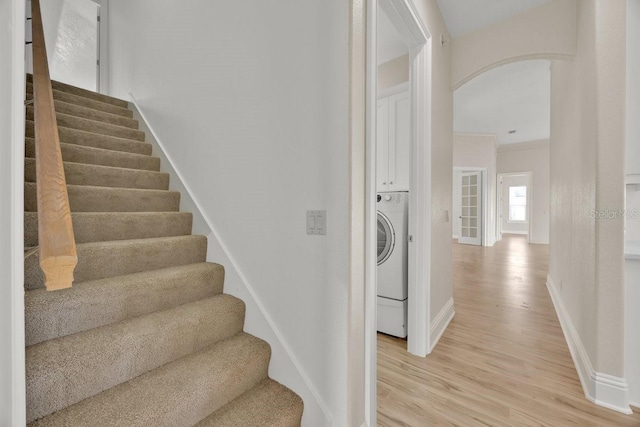 5556 Vintage View Blvd, Lakeland, FL 33812 - stairway featuring arched walkways, baseboards, wood finished floors, and washer / dryer