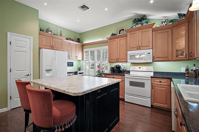 215 Chula Vista Ave, The Villages, FL 32159 - kitchen with white appliances, a kitchen island, dark wood-style flooring, a breakfast bar, and lofted ceiling