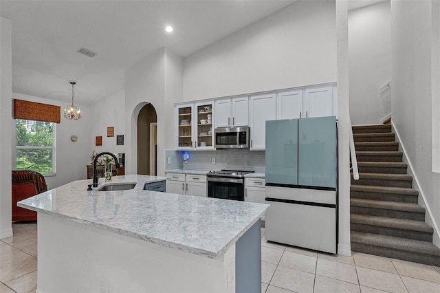 4239 Fawn Meadows Cir, Clermont, FL 34711 - kitchen with appliances with stainless steel finishes, a sink, arched walkways, light tile patterned floors, and backsplash