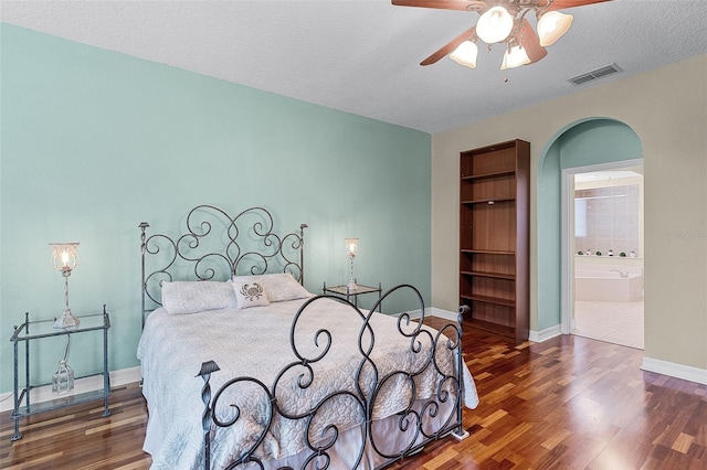 4239 Fawn Meadows Cir, Clermont, FL 34711 - bedroom featuring wood finished floors, a textured ceiling, arched walkways, baseboards, and ensuite bath