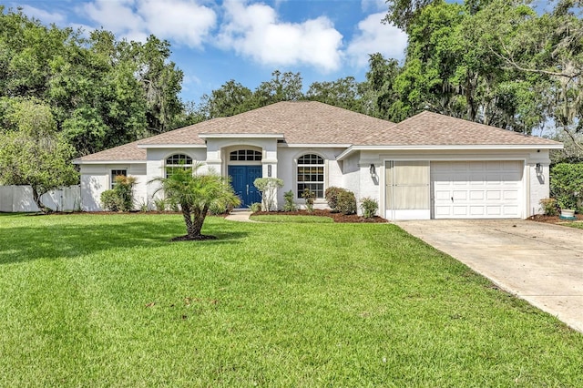 34231 Shadewood Cir, Leesburg, FL 34788 - view of front of house featuring an attached garage, driveway, a front yard, a shingled roof, and stucco siding
