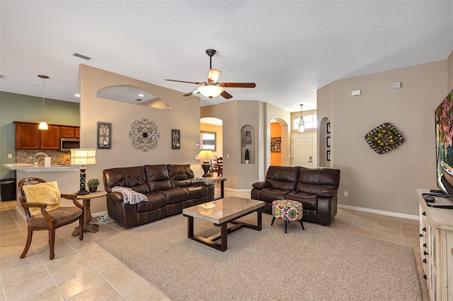 34231 Shadewood Cir, Leesburg, FL 34788 - living room with arched walkways, light tile patterned floors, ceiling fan, and baseboards