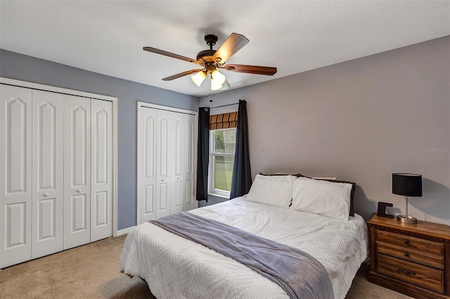 34231 Shadewood Cir, Leesburg, FL 34788 - bedroom featuring light carpet, two closets, a ceiling fan, and baseboards