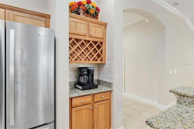 3097 Bureau Path, The Villages, FL 32163 - kitchen with freestanding refrigerator, arched walkways, crown molding, backsplash, and light stone countertops