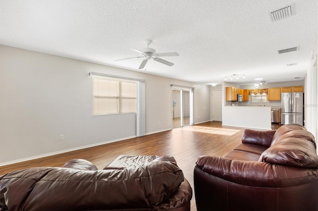 2317 Whisper St, The Villages, FL 32162 - living area featuring wood finished floors, ceiling fan, a textured ceiling, healthy amount of natural light, and baseboards