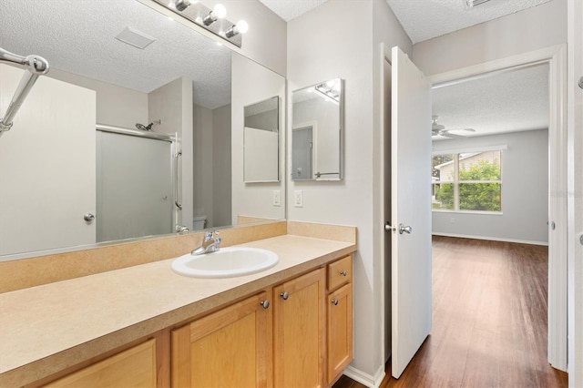2317 Whisper St, The Villages, FL 32162 - full bath featuring a textured ceiling, a shower with door, vanity, wood finished floors, and a ceiling fan