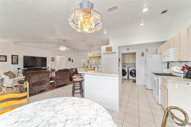 8850 SE 156th St, Summerfield, FL 34491 - kitchen with white appliances, separate washer and dryer, a chandelier, light tile patterned floors, and a kitchen breakfast bar