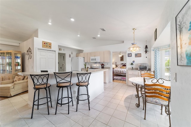 8850 SE 156th St, Summerfield, FL 34491 - kitchen featuring white appliances, light tile patterned floors, vaulted ceiling, an island with sink, and a kitchen bar