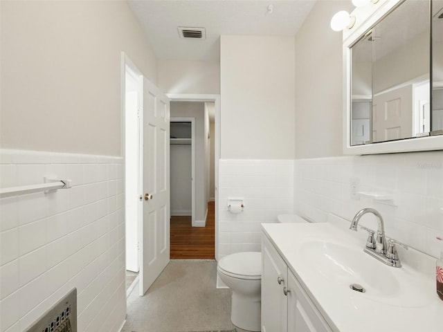 9269 Silver Lake Dr, Leesburg, FL 34788 - bathroom featuring tile walls, vanity, toilet, and wainscoting