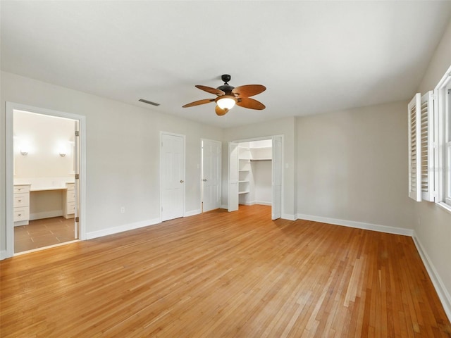 9269 Silver Lake Dr, Leesburg, FL 34788 - unfurnished bedroom featuring light wood-style floors, baseboards, a ceiling fan, and connected bathroom