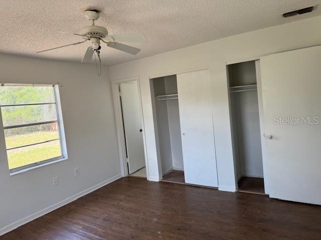 1109 Willow Ct, Tavares, FL 32778 - unfurnished bedroom with multiple closets, wood finished floors, baseboards, a textured ceiling, and a ceiling fan