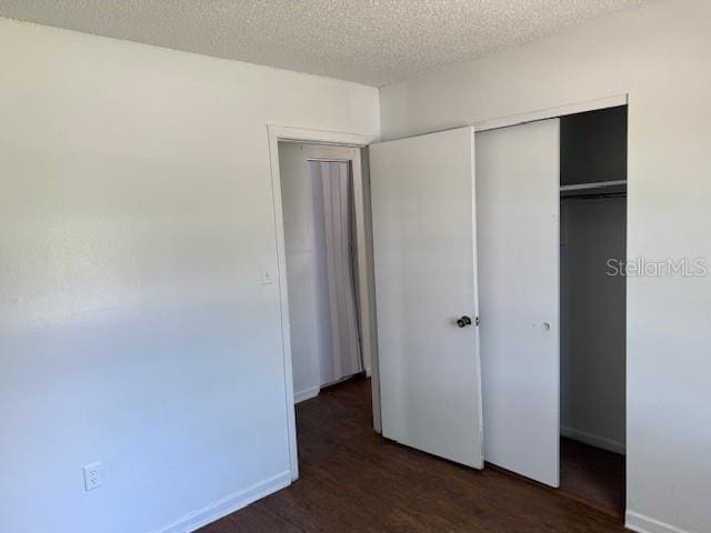1109 Willow Ct, Tavares, FL 32778 - unfurnished bedroom with a closet, dark wood-style flooring, a textured ceiling, and baseboards
