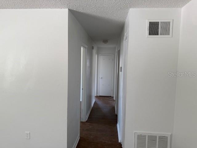 1109 Willow Ct, Tavares, FL 32778 - corridor with a textured ceiling, dark wood-style floors, and baseboards