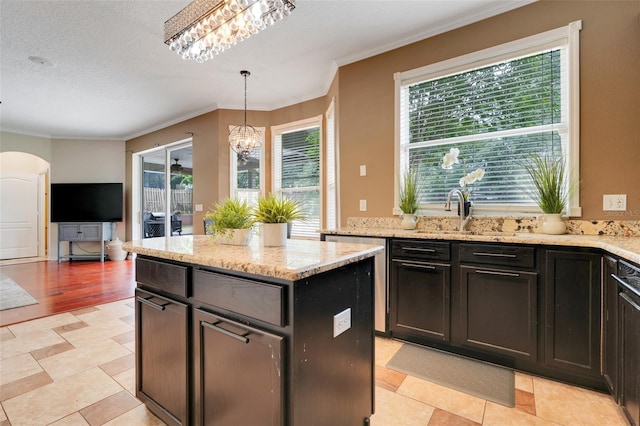 107 Wekiva Pointe Cir, Apopka, FL 32712 - kitchen featuring a sink, crown molding, light stone counters, arched walkways, and hanging light fixtures