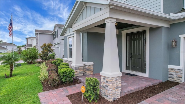 14501 Wabasso Loop, Winter Garden, FL 34787 - view of exterior entry featuring stone siding, stucco siding, a lawn, and board and batten siding