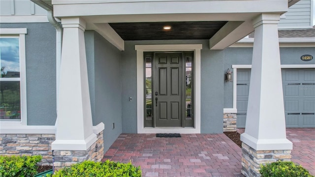 14501 Wabasso Loop, Winter Garden, FL 34787 - doorway to property with stone siding, stucco siding, a garage, and covered porch