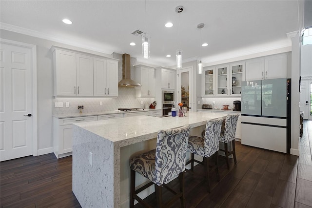 14501 Wabasso Loop, Winter Garden, FL 34787 - kitchen featuring wall chimney range hood, appliances with stainless steel finishes, dark wood finished floors, ornamental molding, and decorative backsplash