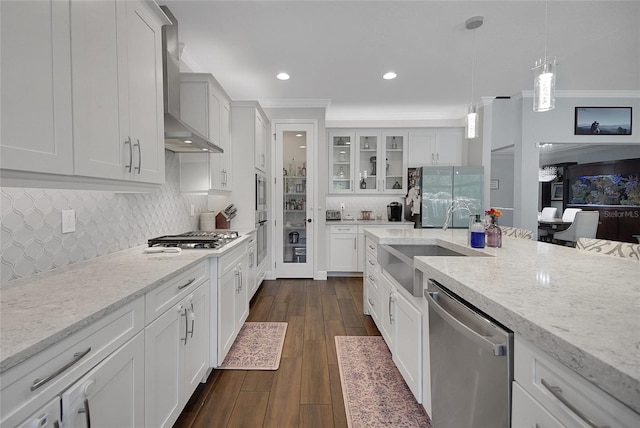 14501 Wabasso Loop, Winter Garden, FL 34787 - kitchen with stainless steel appliances, wall chimney range hood, glass insert cabinets, a sink, and hanging light fixtures