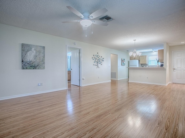 2799 Privada Dr, The Villages, FL 32162 - unfurnished living room featuring a chandelier, a textured ceiling, light wood finished floors, and a ceiling fan