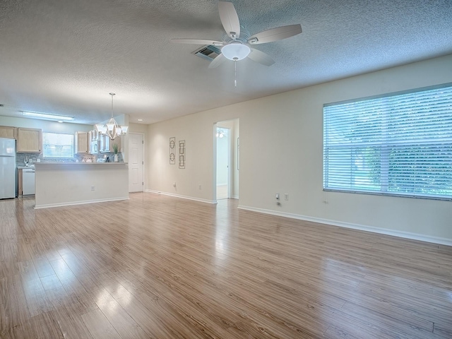 2799 Privada Dr, The Villages, FL 32162 - unfurnished living room with a textured ceiling, a chandelier, light wood finished floors, and a ceiling fan