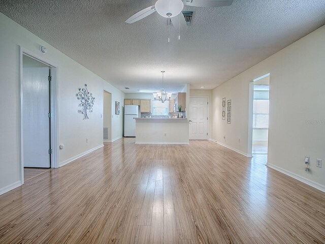 2799 Privada Dr, The Villages, FL 32162 - unfurnished living room featuring a chandelier, light wood-style flooring, ceiling fan, a textured ceiling, and plenty of natural light