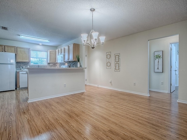 2799 Privada Dr, The Villages, FL 32162 - kitchen with white appliances, a textured ceiling, light wood-style floors, a chandelier, and decorative backsplash