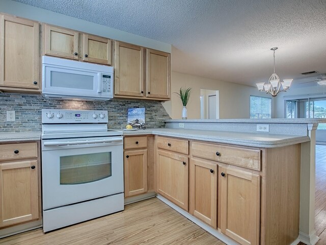 2799 Privada Dr, The Villages, FL 32162 - kitchen with white appliances, light brown cabinetry, a peninsula, light countertops, and light wood finished floors