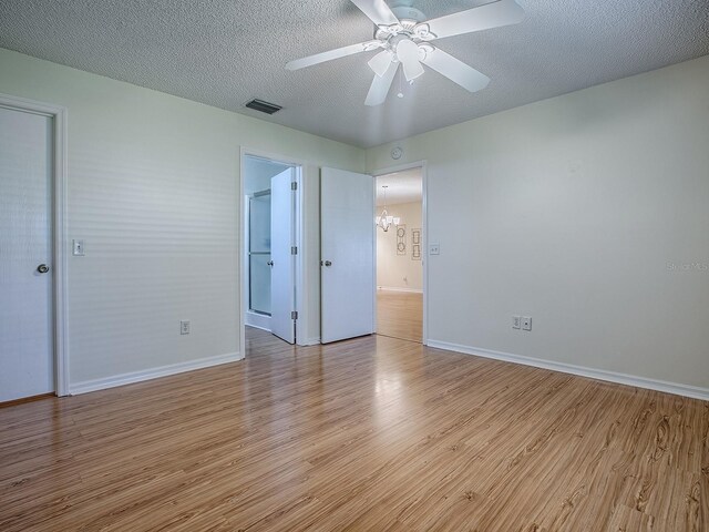 2799 Privada Dr, The Villages, FL 32162 - unfurnished bedroom with light wood-style floors, a chandelier, a walk in closet, a textured ceiling, and a ceiling fan