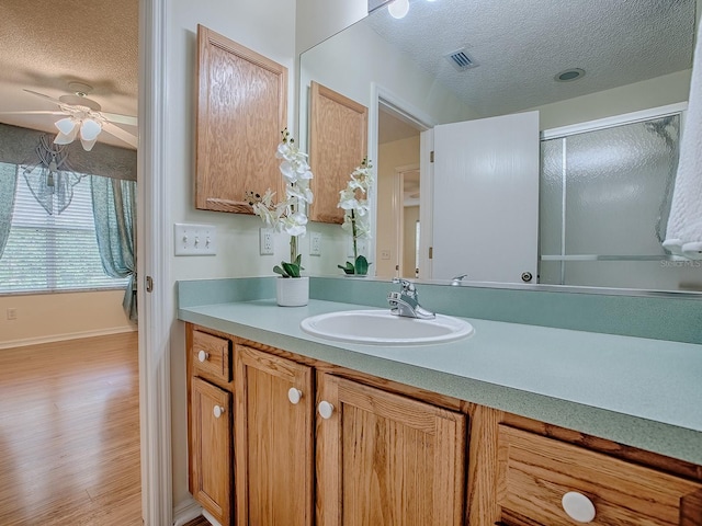 2799 Privada Dr, The Villages, FL 32162 - full bathroom featuring a textured ceiling, vanity, wood finished floors, a ceiling fan, and a shower with shower door