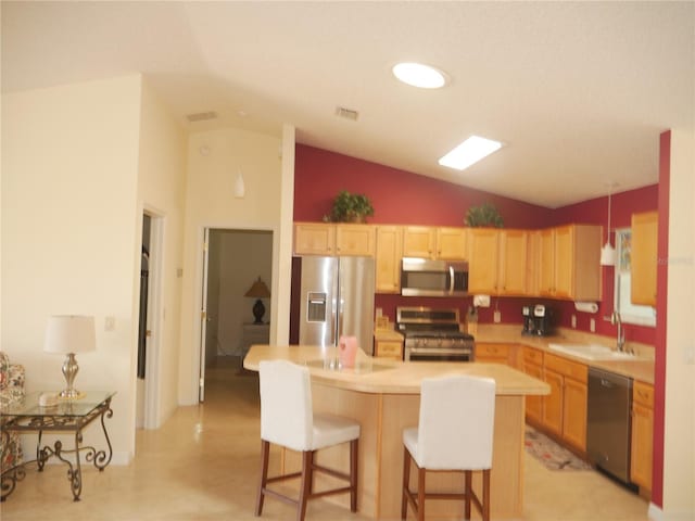 8377 SE 177th Bartram Loop, The Villages, FL 32162 - kitchen featuring appliances with stainless steel finishes, a sink, light brown cabinetry, vaulted ceiling, and a kitchen bar