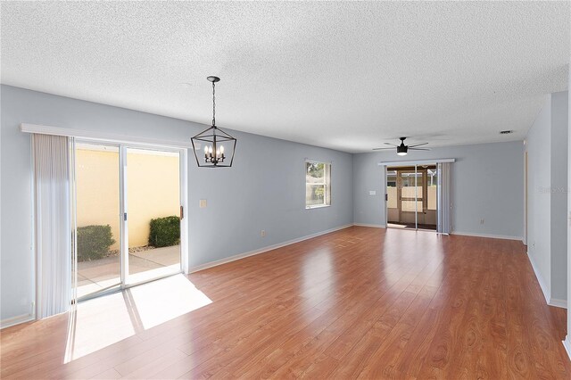 1116 San Bernardo Rd, The Villages, FL 32162 - unfurnished living room with a chandelier, a textured ceiling, light wood finished floors, a ceiling fan, and baseboards