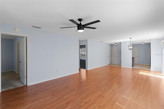 1116 San Bernardo Rd, The Villages, FL 32162 - unfurnished living room with a ceiling fan, light wood finished floors, a textured ceiling, and baseboards