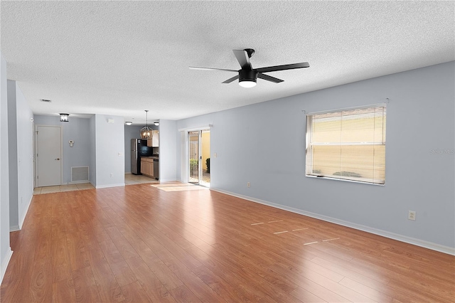 1116 San Bernardo Rd, The Villages, FL 32162 - unfurnished living room with a ceiling fan, light wood-style floors, a textured ceiling, and baseboards