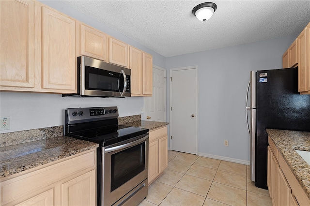 1116 San Bernardo Rd, The Villages, FL 32162 - kitchen featuring appliances with stainless steel finishes, light brown cabinets, light tile patterned floors, a textured ceiling, and stone counters