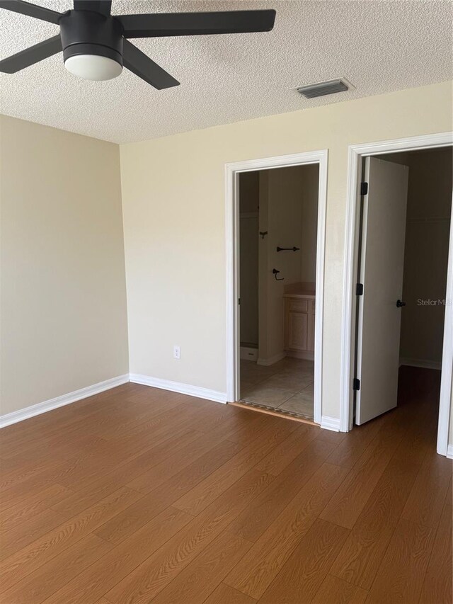 1116 San Bernardo Rd, The Villages, FL 32162 - unfurnished bedroom featuring wood finished floors, a textured ceiling, connected bathroom, ceiling fan, and baseboards