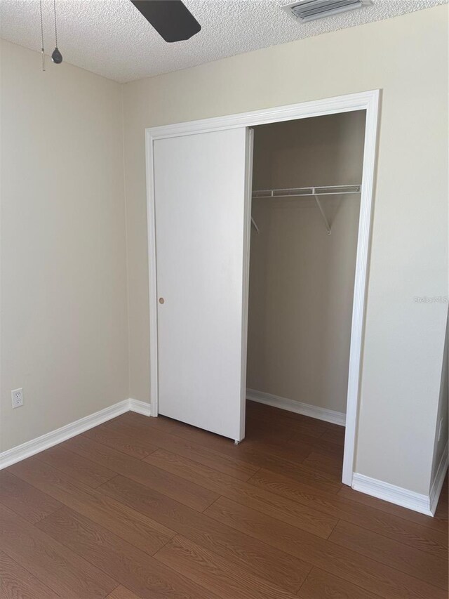 1116 San Bernardo Rd, The Villages, FL 32162 - unfurnished bedroom with wood finished floors, a closet, baseboards, a textured ceiling, and a ceiling fan