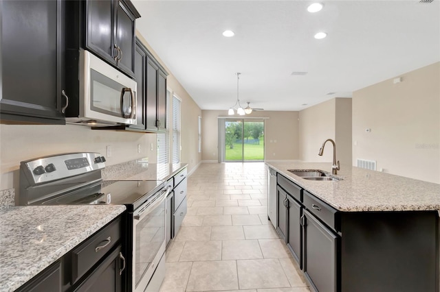 15531 Waterleigh Cove Dr, Winter Garden, FL 34787 - kitchen with stainless steel appliances, an island with sink, recessed lighting, dark cabinetry, and light tile patterned floors