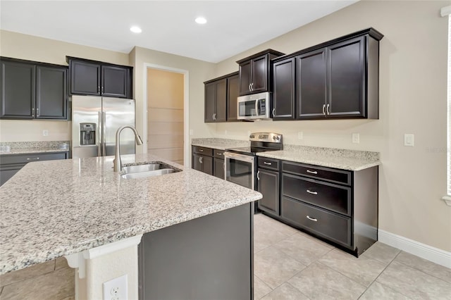 15531 Waterleigh Cove Dr, Winter Garden, FL 34787 - kitchen featuring appliances with stainless steel finishes, a center island with sink, light stone countertops, light tile patterned flooring, and recessed lighting
